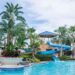A water park at a family resort, surrounded by palm trees and a clear blue sky, inviting families to enjoy a fun experience.